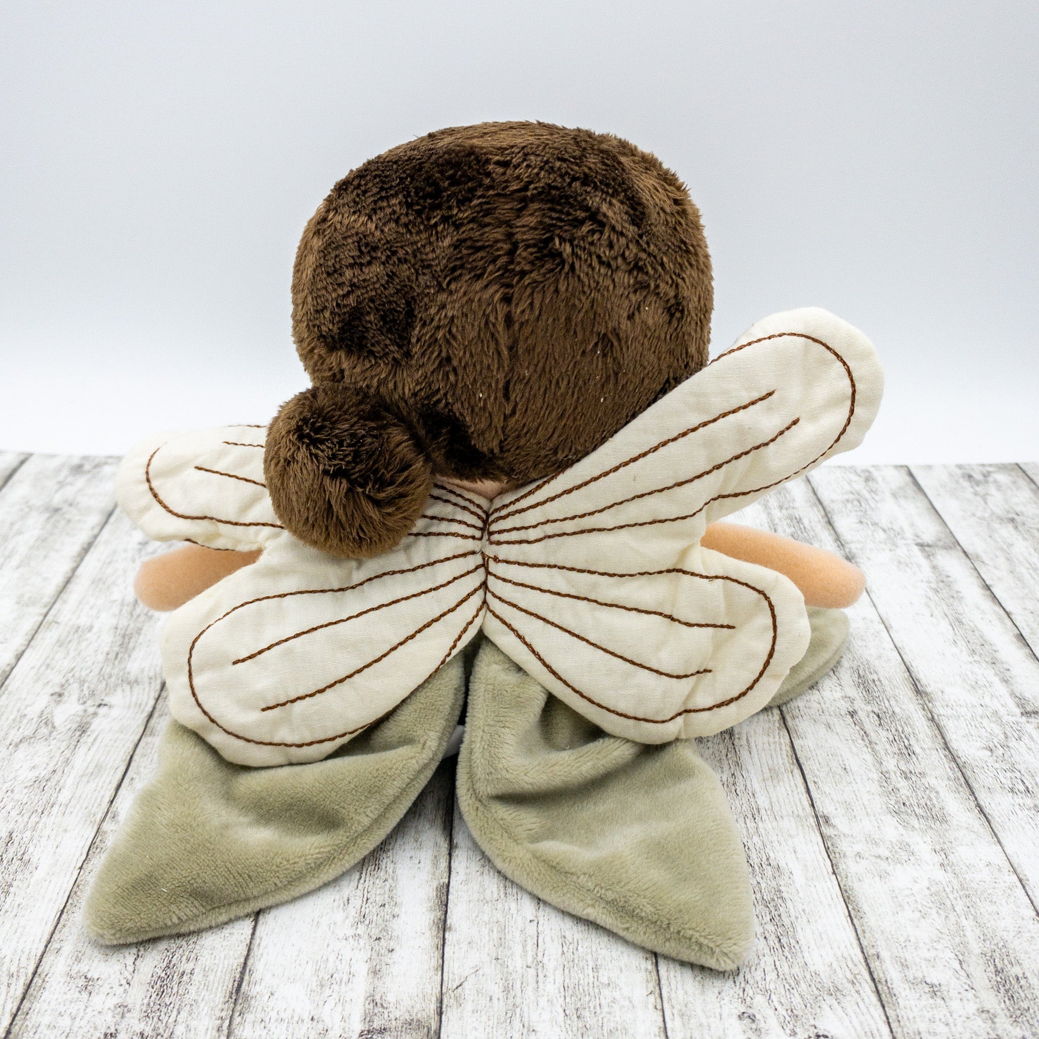 Handgefertigte Feenpuppe aus weichem Stoff in Beige, mit filigranen Flügeln, gesticktem Namen auf dem Kleid, braunen Haaren und liebevollen Details wie Ballerinaschuhen. Ideal als personalisiertes Geschenk für Kinder.
