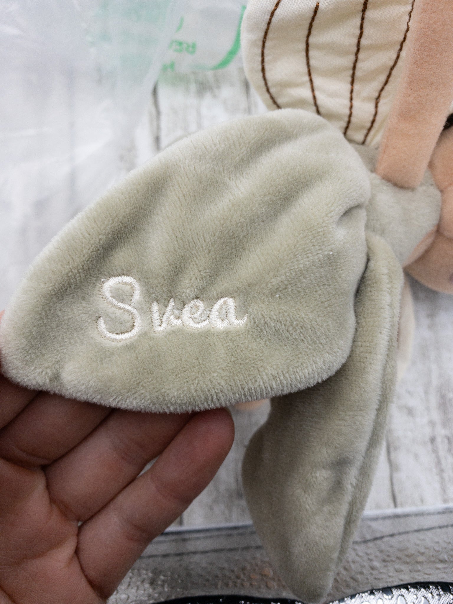 Handgefertigte Feenpuppe aus weichem Stoff in Beige, mit filigranen Flügeln, gesticktem Namen auf dem Kleid, braunen Haaren und liebevollen Details wie Ballerinaschuhen. Ideal als personalisiertes Geschenk für Kinder.