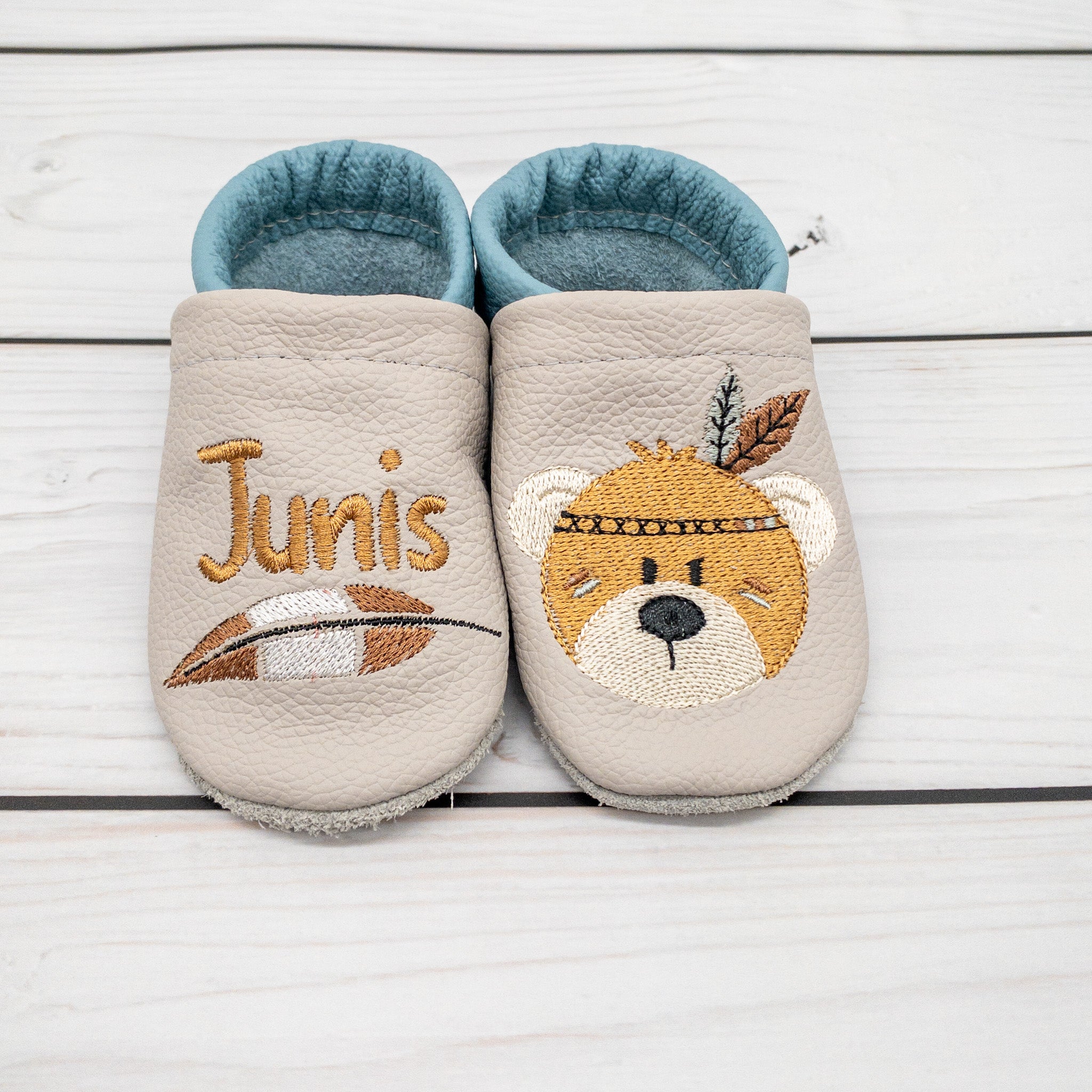 Krabbelschuhe von Krabbelhelden in grün und braun mit Bär und Federschmuck und Name bestickt.