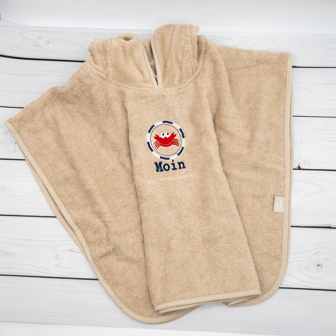 Badeponcho von Krabbelhelden, beige mit Namen und Krebs bestickt.