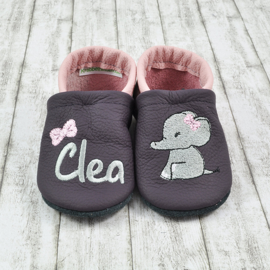 Weiche Krabbelschuhe von Krabbelhelden in lila und rosa mit Elefant und Name bestickt.