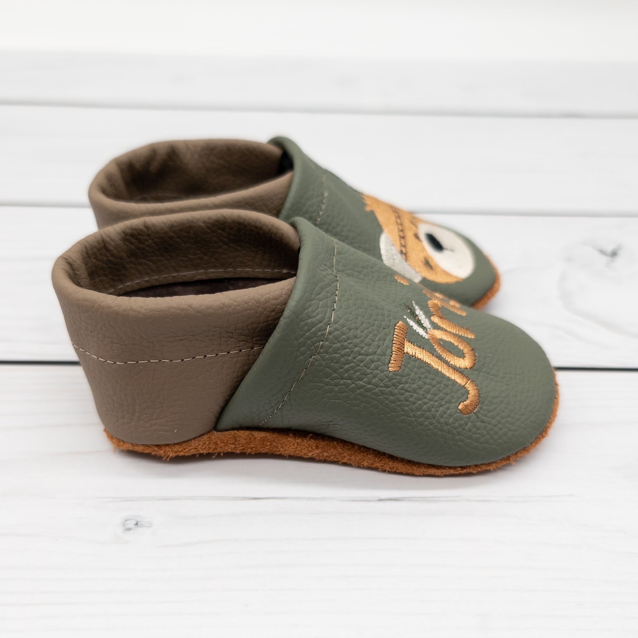 Krabbelschuhe von Krabbelhelden in grün und braun mit Bär und Federschmuck und Name bestickt.